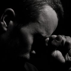 Sad man in darkness with his hand to his head
