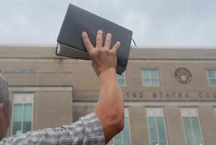 Man holding a religious text in the air in protest