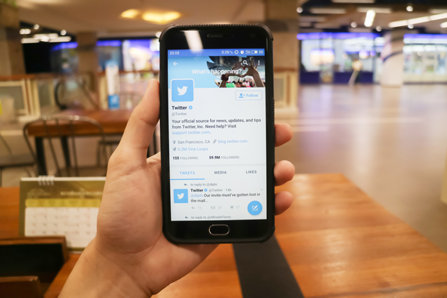 Man holding phone with Twitter open on it