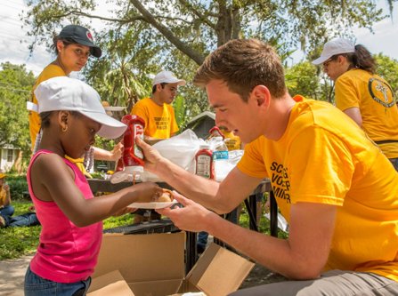 A Scientology Volunteer Minister provides food to a little girl
