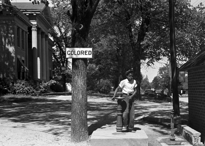 A young black boy drinking out of the “colored“ water fountain