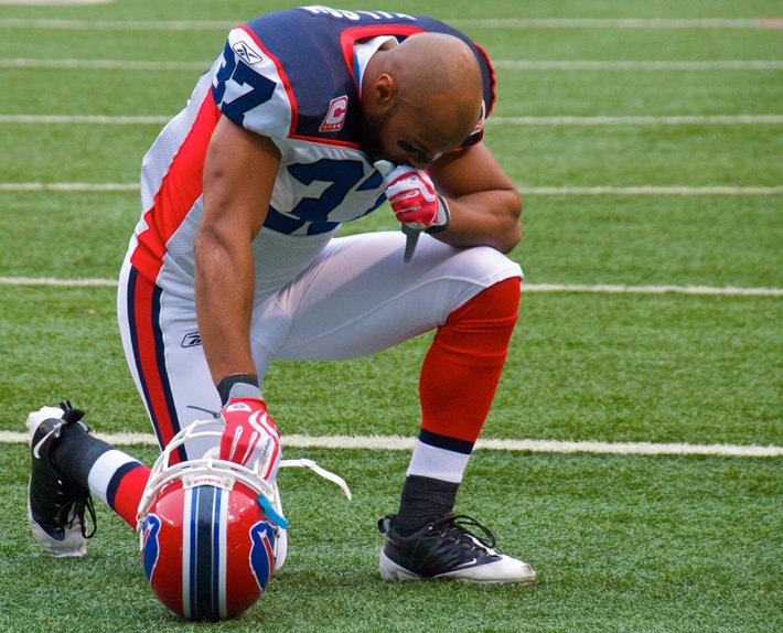 Football player kneeling in prayer