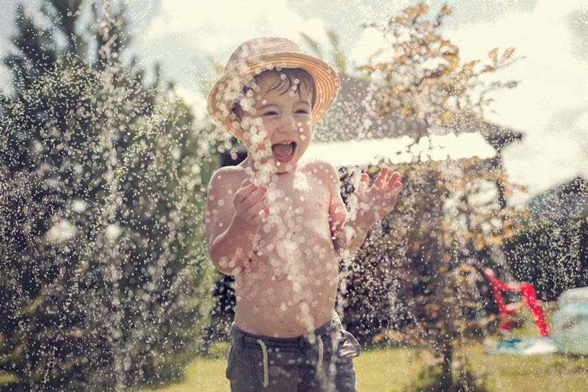 Child playing in sprinkler