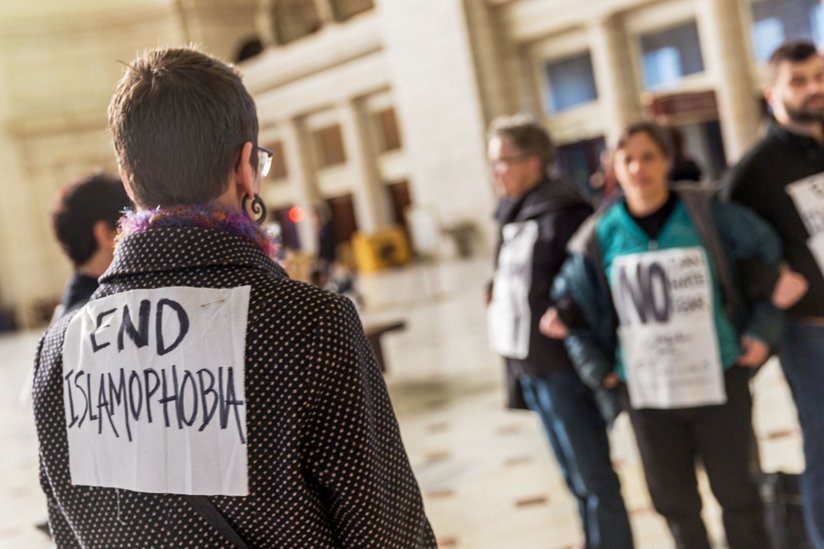 A woman wearing a sign that says “End Islamophobia”