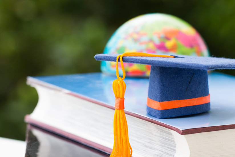 Textbook, globe and graduate hat